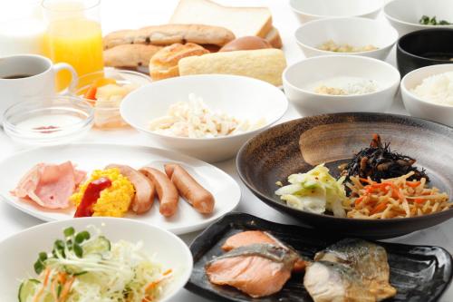 una mesa con platos de comida y tazones de comida en Vessel Inn Hiroshima Ekimae en Hiroshima