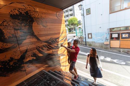 a man and a woman standing in front of a wall at Sakura Cross Hotel Shinjuku East in Tokyo