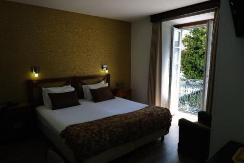 a bedroom with a bed and a large window at Hotel Dona Sofia in Braga