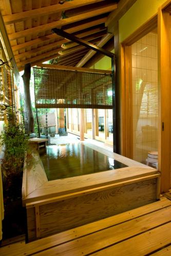 a swimming pool in a house with a wooden tub at Yufuin Santoukan in Yufuin
