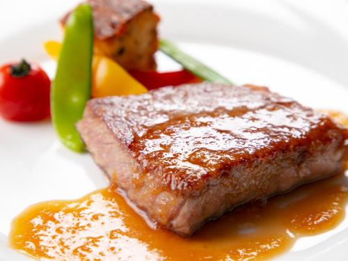 a piece of meat on a white plate with sauce at Iwakuni Kokusai Kanko Hotel in Iwakuni