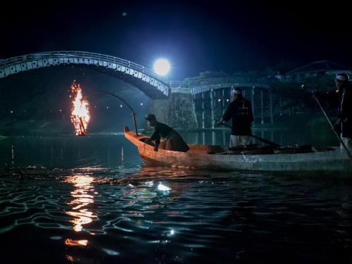 two men in a boat on the water at night at Iwakuni Kokusai Kanko Hotel in Iwakuni