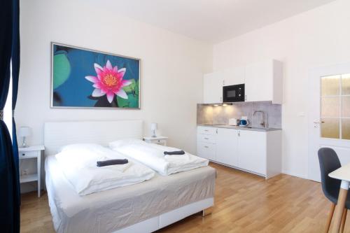 a white bedroom with a bed and a kitchen at Bouquet Apartments in Prague
