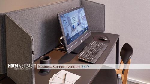 a computer monitor and a keyboard and mouse on a desk at Hotel Wettstein in Basel