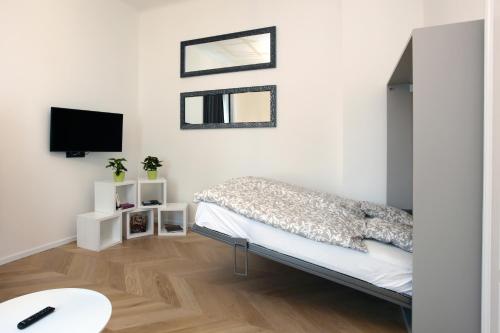 The Apartment House - Mezibranska في براغ: غرفة نوم بيضاء مع سرير وتلفزيون