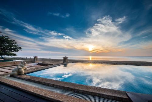 a swimming pool with the sun setting over the ocean at Amara Villa Khao Ka Lok in Ban Nong Sua