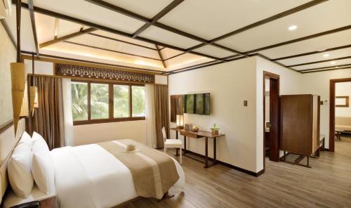 a bedroom with a bed and a desk and a window at North Zen Villas in Panglao