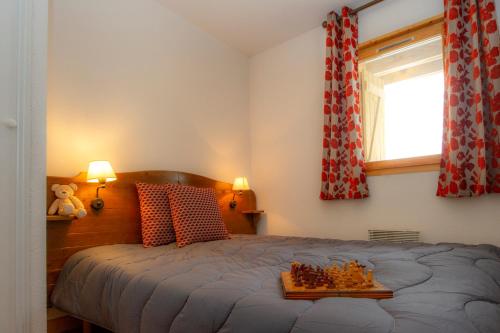 a bedroom with a bed with a tray of chessetts on it at Résidence Goélia Les Chalets de Saint-Sorlin in Saint-Sorlin-dʼArves