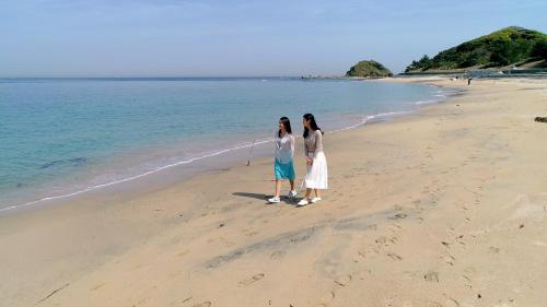 two women standing on a beach near the water at Kyukamura Shikanoshima in Fukuoka