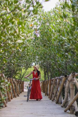 a woman in a red dress with a bike on a bridge at North Zen Villas in Panglao