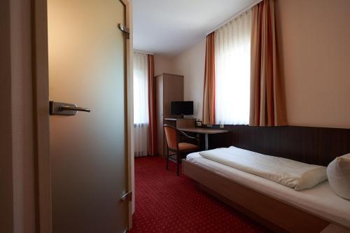 Hotel Gasthof König Karl في فرودنستاد: غرفة في الفندق بها سرير ومكتب وبه جهاز كمبيوتر