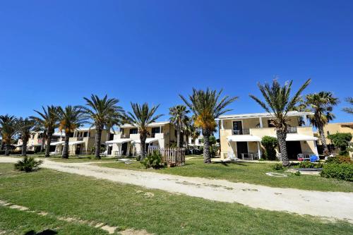 a row of houses on the beach with palm trees at Resort Santa Maria Hotel in Birgi Vecchi