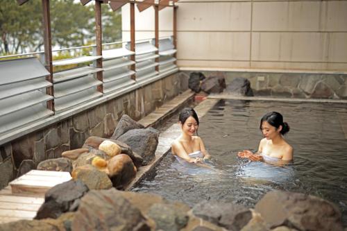 two women are bathing in a pool of water at Kyukamura Shikanoshima in Fukuoka
