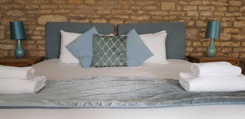 a bed with blue and white pillows on it at The Kings Arms Hotel in Stow on the Wold