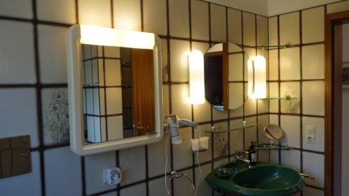 een badkamer met een wastafel, een spiegel en verlichting bij Ferienhaus Schils Zur alten Heidegärtnerei in Bispingen
