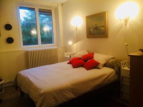 Schlafzimmer mit einem Bett mit roten Kissen und einem Fenster in der Unterkunft Les Moulins de Requeugne in Tauxigny