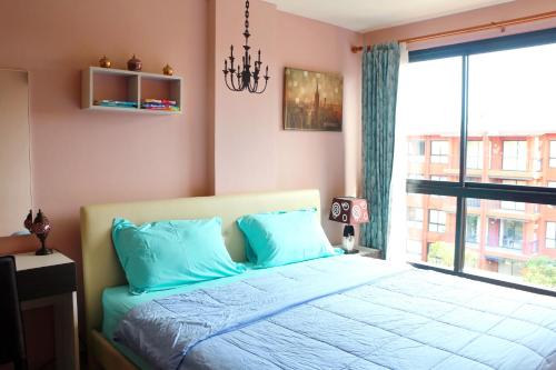 a bedroom with a bed with blue pillows and a window at Bluroc Huahin 15/684 in Hua Hin