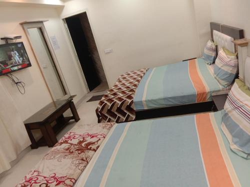 a bedroom with two beds and a tv in it at Oscar Banquet and Hotel in Kālka