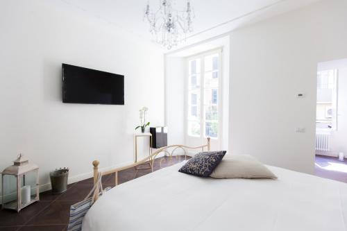 a white bedroom with a bed and a flat screen tv at Alessia's Place in Como