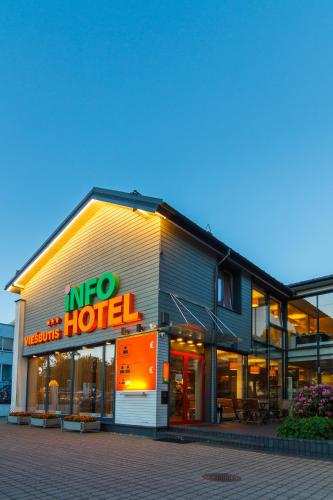 a hotel with a neon sign in front of it at Info Hotel in Palanga