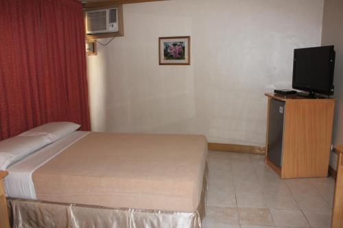 a hotel room with a bed and a television at Elegant Circle Inn in Cebu City