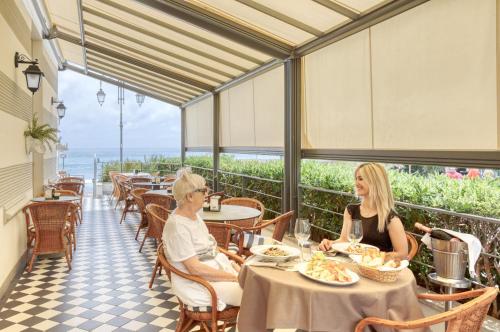a man and woman sitting at a table in a restaurant at Hotel Lido in Alassio
