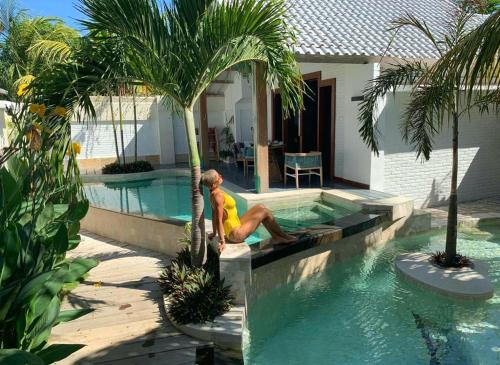 un hombre sentado en una piscina junto a una palmera en The White Key Luxury Villas, en Gili Trawangan
