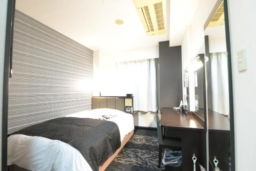 una camera con letto, scrivania e specchio di APA Hotel Suzuka-Chuou a Suzuka