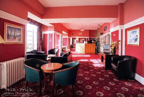 uma sala de estar com paredes e cadeiras vermelhas e uma mesa em The Southcliff Hotel em Folkestone