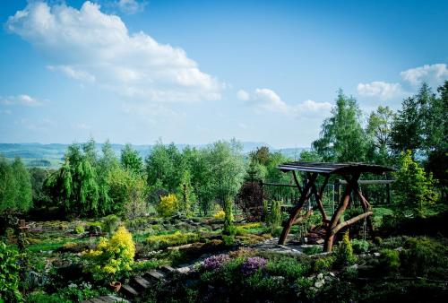 a wooden structure in a garden with flowers and trees at Apartamenty Romanowka in Raszów