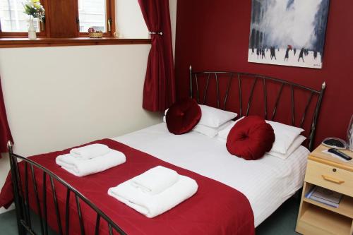 1 dormitorio con 1 cama con sábanas rojas y almohadas rojas en Rosemount Palace, en Aberdeen