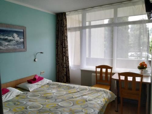 a bedroom with a bed and a table and a window at Concordia in Jūrmala