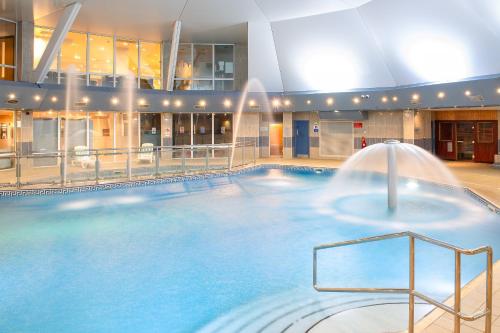 a large swimming pool with a fountain in a building at St Mellion Estate in St Mellion