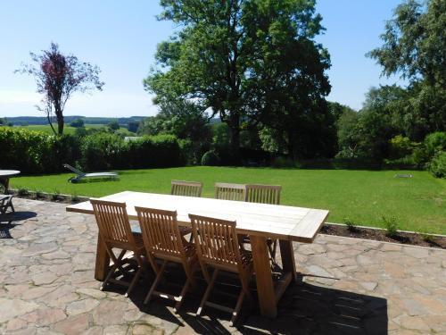 una mesa de picnic de madera con 4 sillas y un campo en L'Aubier, en Tenneville