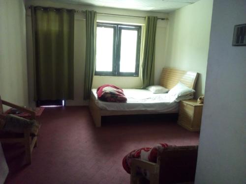 a small bedroom with a bed and a window at Abbott Hills Guest House in Kāgān