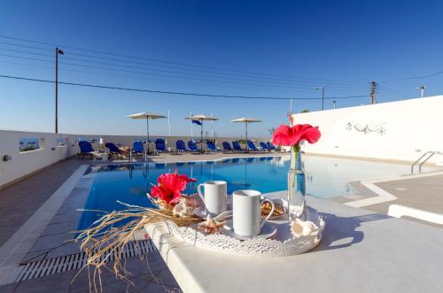 a table with flowers in a vase next to a pool at Aglaia Apartments in Stalida