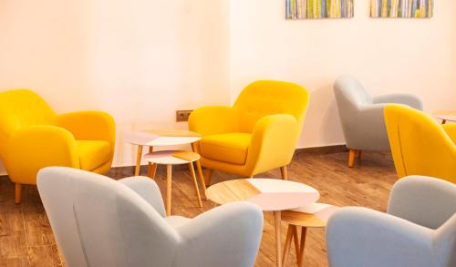 a waiting room with yellow chairs and tables at Hotel Bari in Conil de la Frontera