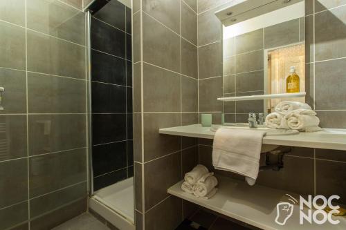 ein Bad mit einer Dusche, einem Waschbecken und Handtüchern in der Unterkunft NOCNOC - Le Rayonnant in Lyon