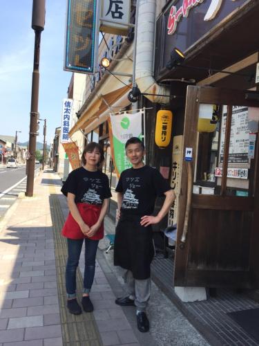 two people standing on a sidewalk in front of a building at Guest house daisho oshiro asobi in Matsue