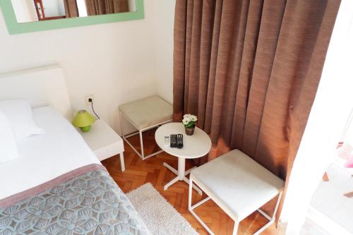 Habitación pequeña con cama, mesa y sillas en Epidaurum Apartments en Cavtat