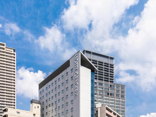 大阪的住宿－Hotel Gracery Osaka Namba，一座高大的白色建筑,背后是天空