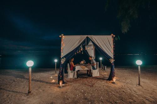 two people sitting at a table in a tent at night at Sea Valley Resort in Lipa Noi