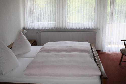 a white bed in a bedroom with windows at Haus Klosterblick in Kröv