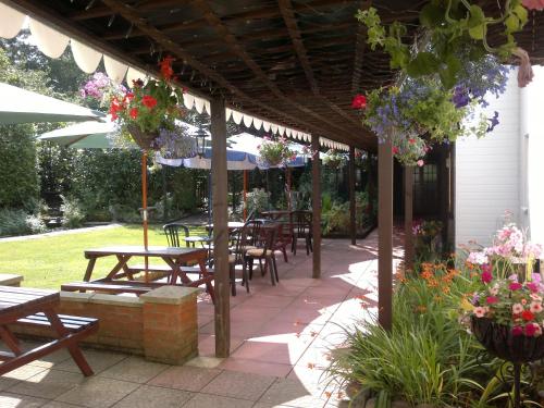 a patio with tables and chairs and umbrellas at Andel Lodge in Kings Lynn