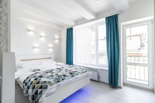 a white bedroom with a bed and a large window at VIP Apartment in Lviv