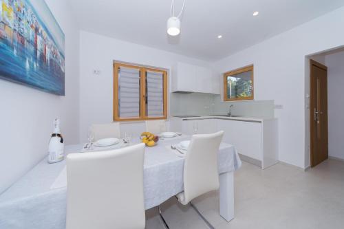 a white kitchen with a white table and chairs at A&J deluxe apartment in Biograd na Moru