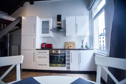a kitchen with white cabinets and a stove top oven at Luxury Suites Cathedral by Rikas Hotels in Antwerp