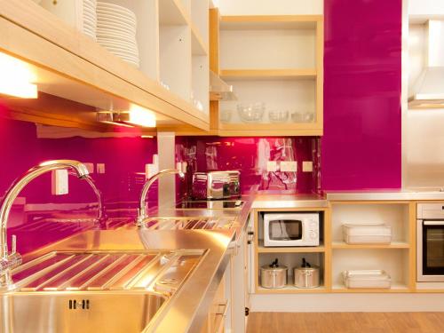 een keuken met paarse muren en een roestvrijstalen wastafel bij YHA Stratford-Upon-Avon in Stratford-upon-Avon