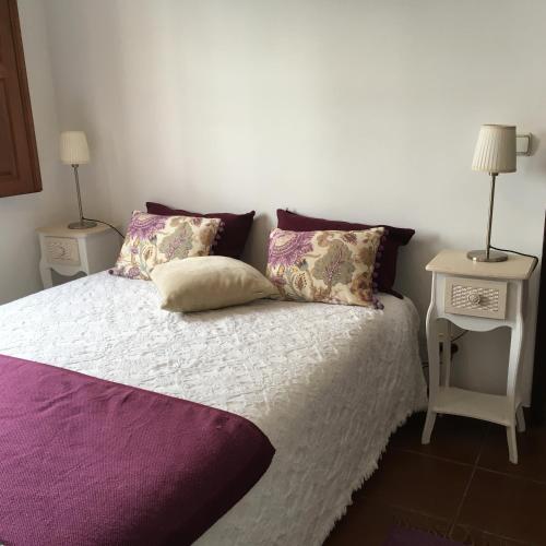 a bedroom with a bed with purple sheets and pillows at Studio do Brejo - de 2 a 3 pessoas in Vila Nova de Milfontes