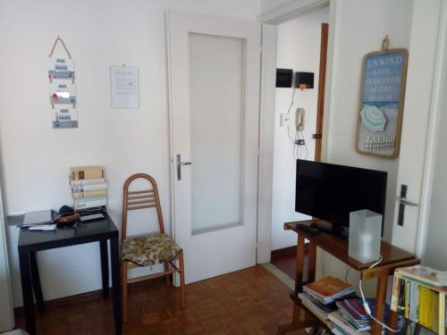 a living room with a television and a chair and a door at Appartamento Perco Riva Dandolo in Grado